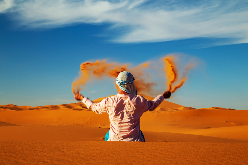 Single,Man,Throws,Sand,In,The,Sahara,Desert,At,Sunset.